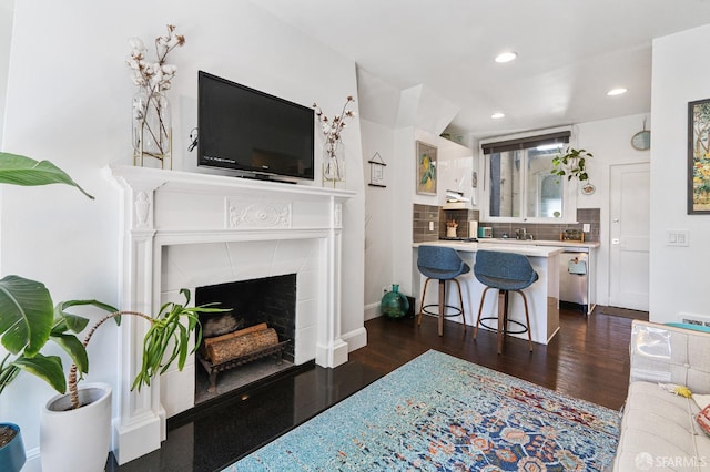 living room with dark hardwood / wood-style flooring and a tiled fireplace