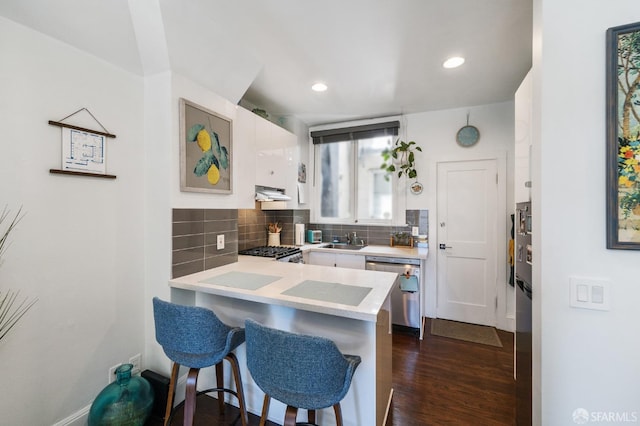 kitchen featuring dishwasher, white cabinetry, tasteful backsplash, sink, and a breakfast bar