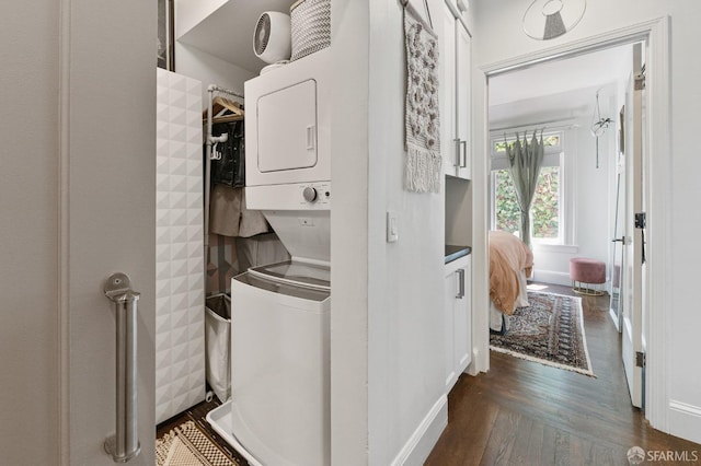 clothes washing area featuring stacked washer and dryer and dark hardwood / wood-style flooring