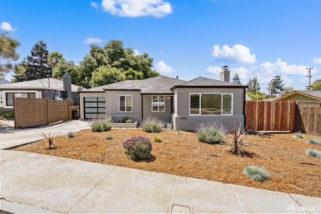 view of front of home with fence, a chimney, a garage, and concrete driveway