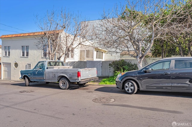 exterior space with a tiled roof, fence, and stucco siding