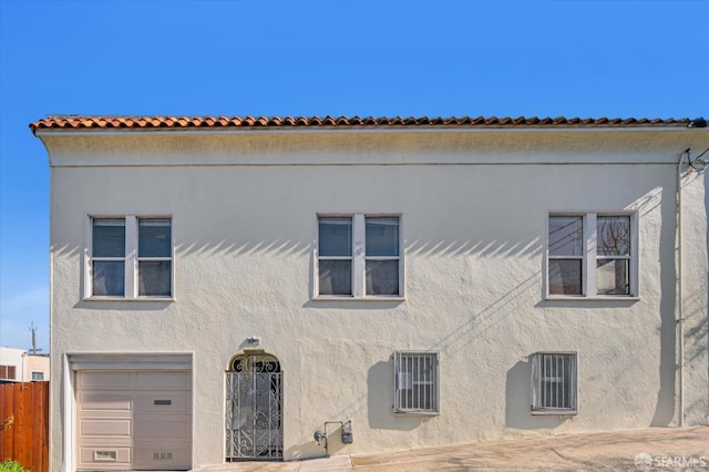 mediterranean / spanish-style home with fence, an attached garage, and stucco siding