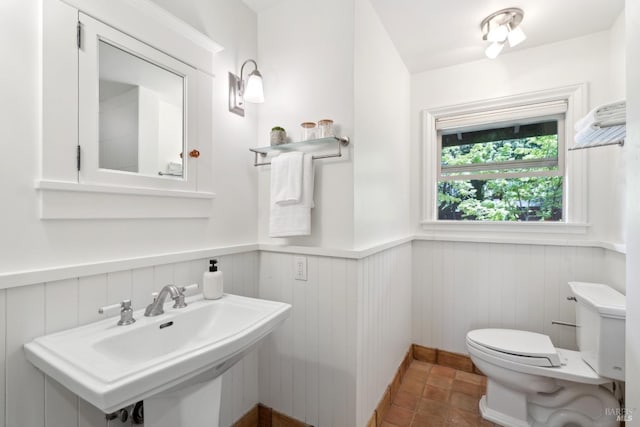 bathroom featuring toilet, a sink, and a wainscoted wall