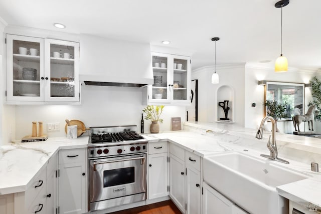 kitchen with premium range hood, premium stove, a sink, and white cabinets
