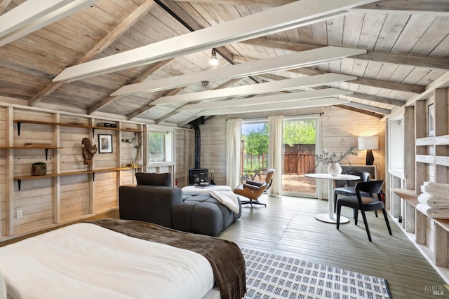 bedroom featuring wood walls, a wood stove, multiple windows, and hardwood / wood-style floors