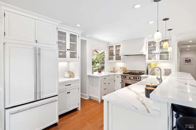kitchen featuring custom exhaust hood, high quality appliances, a peninsula, white cabinets, and a breakfast bar area