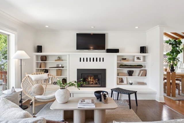 living area featuring crown molding, recessed lighting, a glass covered fireplace, and wood finished floors