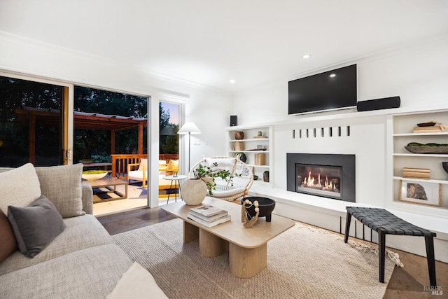 living room featuring a glass covered fireplace, recessed lighting, built in features, and crown molding
