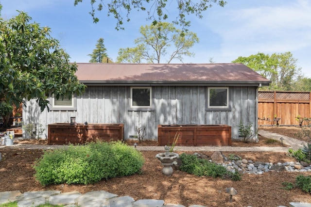 view of front of home with board and batten siding, fence, and metal roof