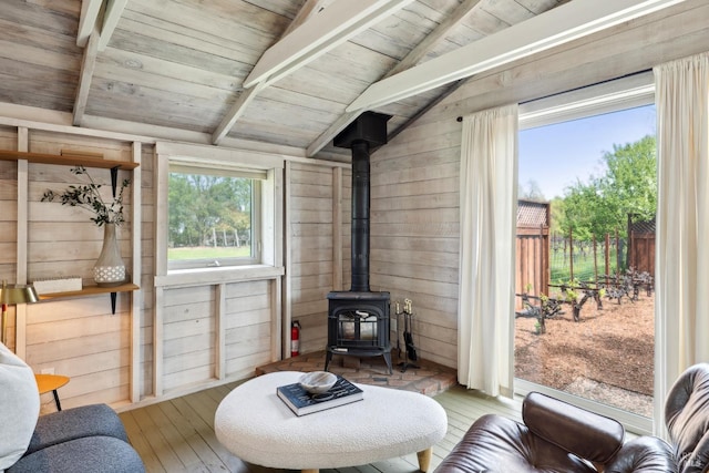 living area with wood walls, a wood stove, wood-type flooring, and wooden ceiling