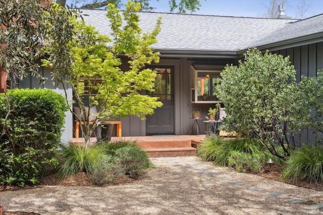 view of exterior entry with board and batten siding, a shingled roof, and covered porch