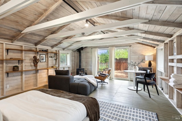 bedroom with wood walls, a wood stove, multiple windows, and hardwood / wood-style flooring