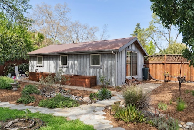 rear view of property with board and batten siding and fence