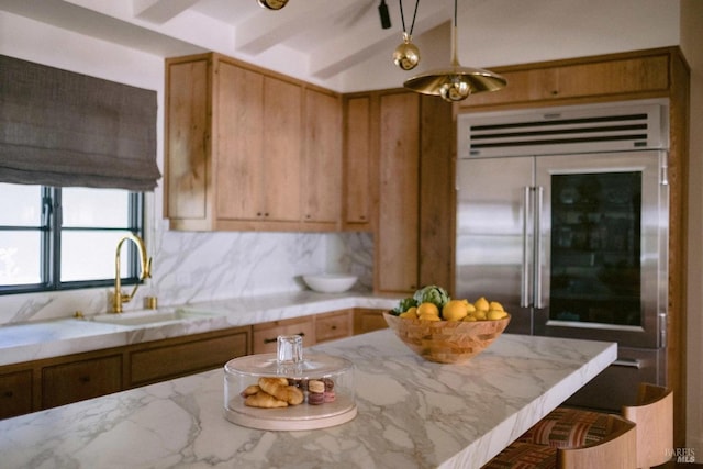 kitchen with light countertops, high quality fridge, and a sink