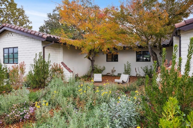 view of side of property featuring a tile roof and stucco siding