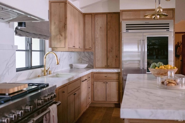 kitchen featuring a sink, decorative backsplash, high end appliances, and light countertops