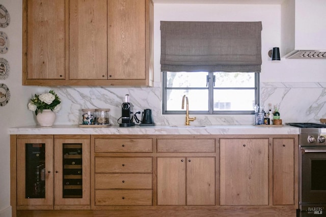 kitchen featuring light countertops, glass insert cabinets, gas stove, a sink, and exhaust hood