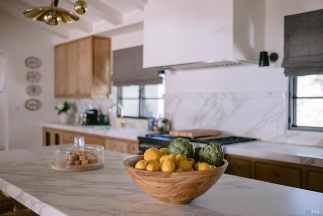 kitchen featuring gas cooktop, wall chimney exhaust hood, light countertops, and decorative backsplash