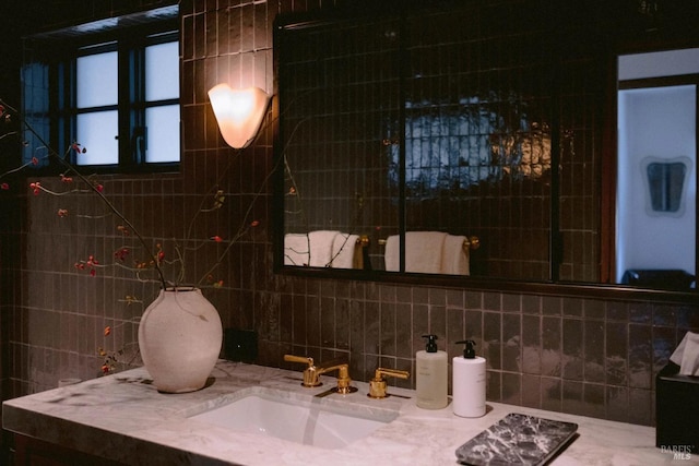 bathroom with tasteful backsplash, a sink, and tile walls