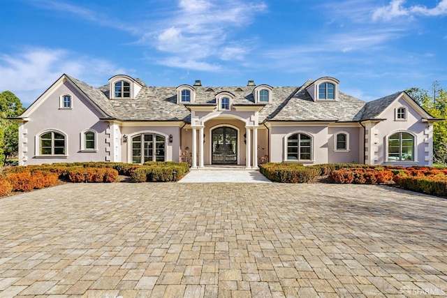 french country style house with a high end roof and stucco siding