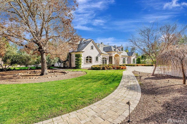 french provincial home with stucco siding and a front yard