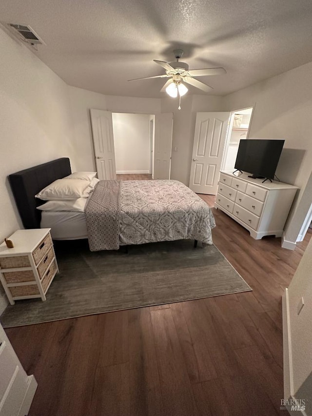 bedroom with ceiling fan, dark hardwood / wood-style floors, and a textured ceiling