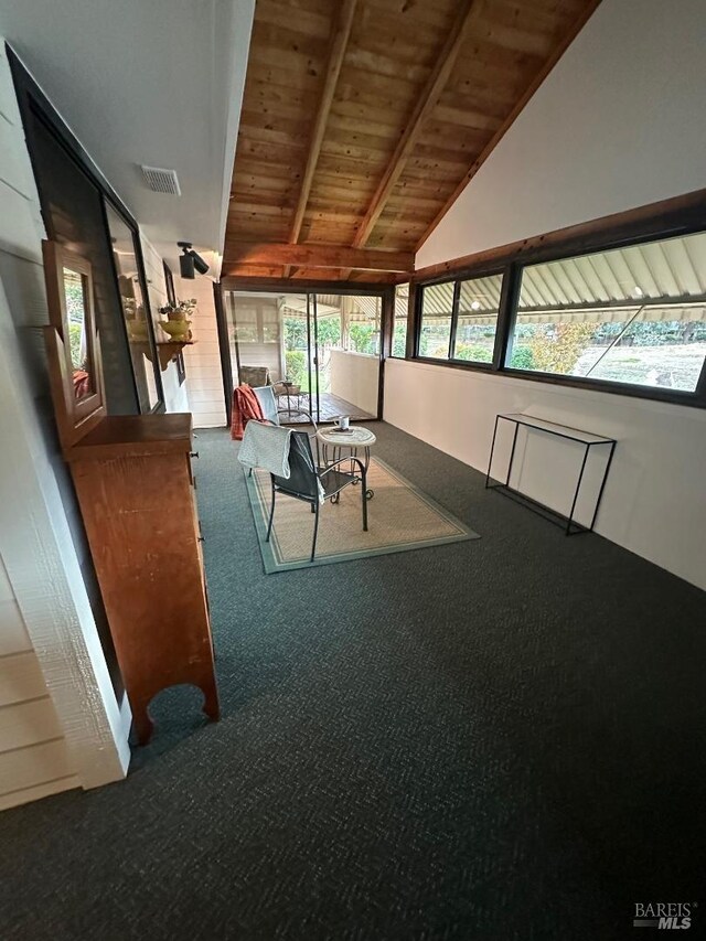 unfurnished dining area with carpet, plenty of natural light, and lofted ceiling with beams