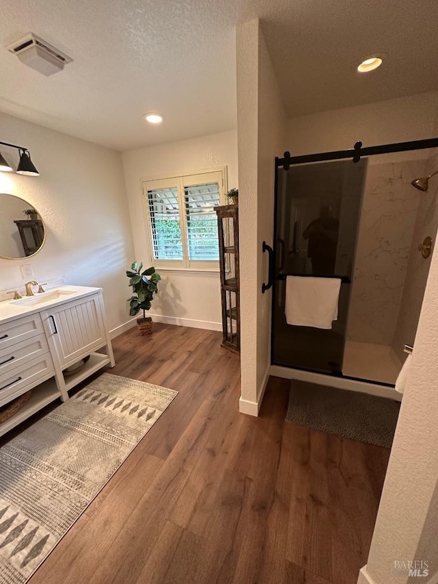 bathroom featuring a shower, hardwood / wood-style floors, vanity, and a textured ceiling