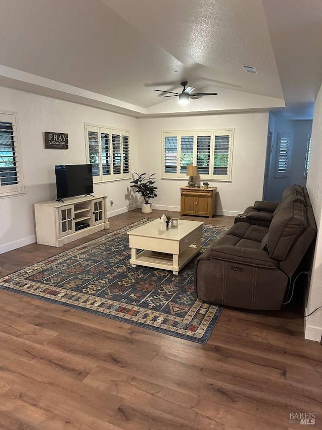 living room with dark wood-type flooring, vaulted ceiling, a textured ceiling, and ceiling fan