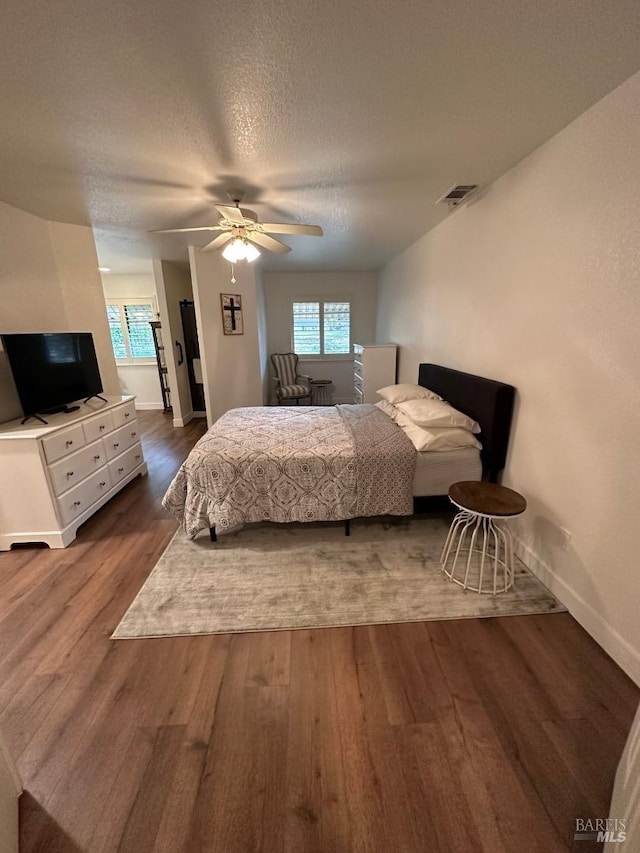 bedroom featuring ceiling fan, a textured ceiling, and dark wood-type flooring