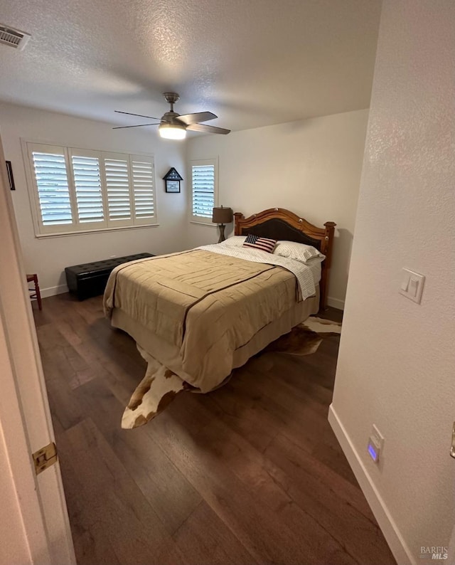 bedroom featuring ceiling fan, a textured ceiling, and dark wood-type flooring