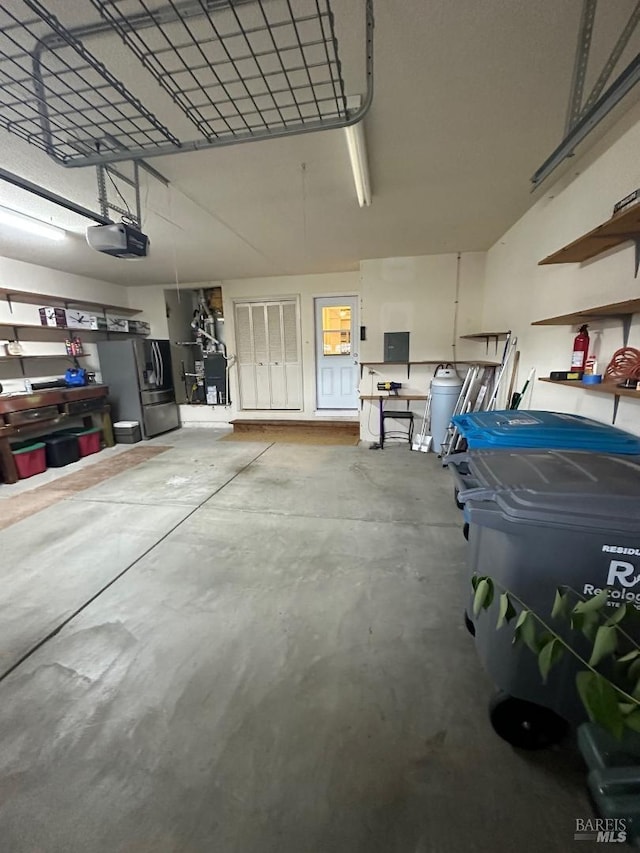 garage featuring a garage door opener, electric panel, and stainless steel refrigerator