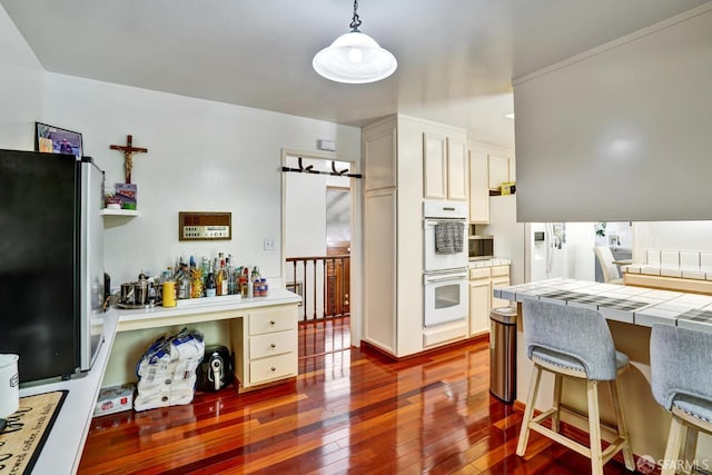 3410 Big Oak Ct, Hayward, CA 94542 - kitchen with white double oven, dark wood-style floors, tile countertops, freestanding refrigerator, and pendant lighting