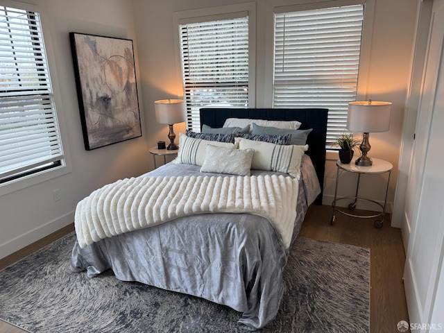 bedroom with multiple windows, baseboards, and wood finished floors