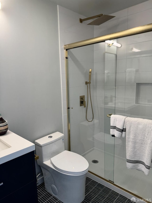 bathroom featuring a stall shower, tile patterned flooring, vanity, and toilet