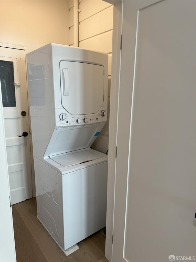 washroom with laundry area, stacked washer / dryer, and wood finished floors