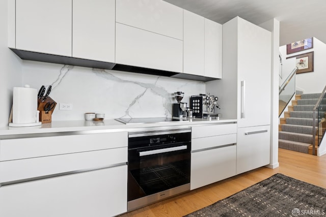 131 Missouri St Unit 402, San Francisco, CA 94107 - kitchen with oven, black electric cooktop, white cabinets, modern cabinets, and light wood-type flooring