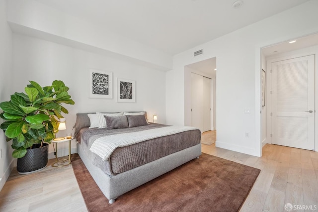 bedroom featuring baseboards, light wood-style floors, and visible vents