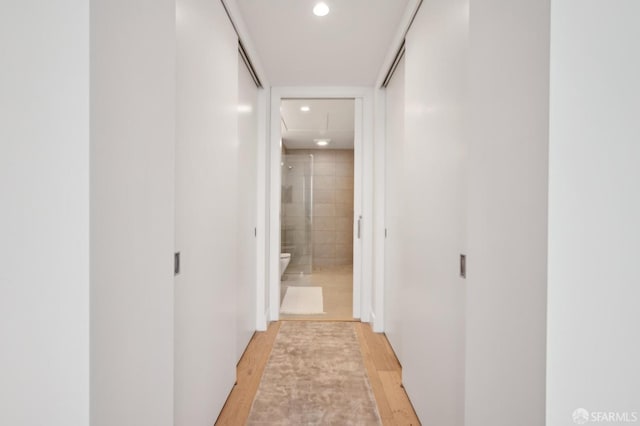 hall with attic access, light wood finished floors, and recessed lighting