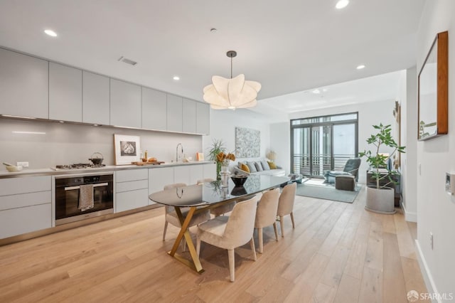 kitchen featuring visible vents, gas cooktop, stainless steel oven, light wood-style floors, and open floor plan