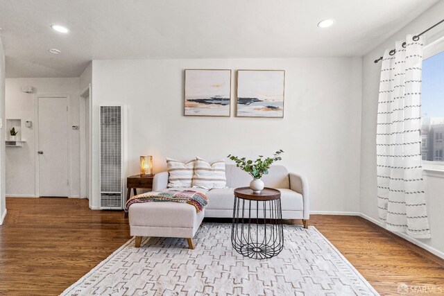 sitting room with baseboards, a heating unit, wood finished floors, and recessed lighting