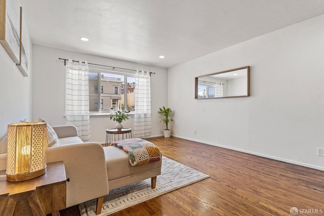 living area with baseboards, wood finished floors, and recessed lighting