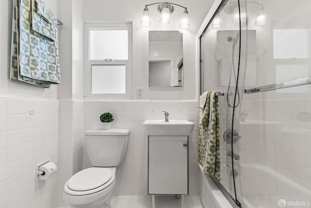 bathroom with tile walls, shower / bath combination, toilet, wainscoting, and vanity