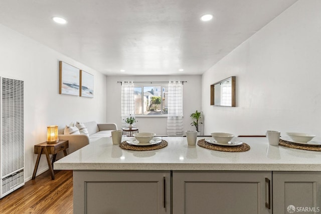 kitchen with recessed lighting, gray cabinetry, wood finished floors, light stone countertops, and a heating unit