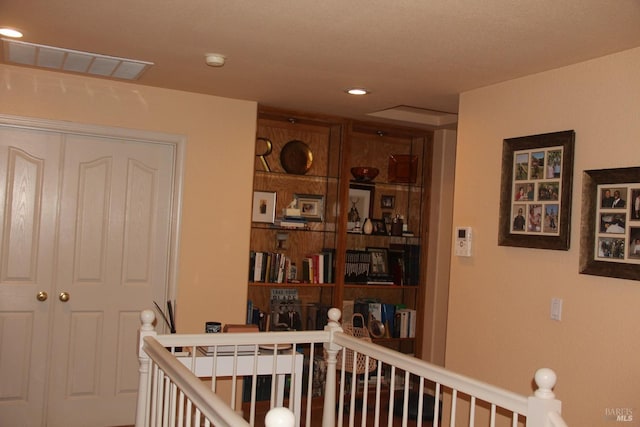 hallway featuring visible vents, an upstairs landing, and recessed lighting