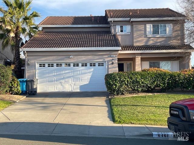 traditional-style home featuring a garage, driveway, a tile roof, and stucco siding