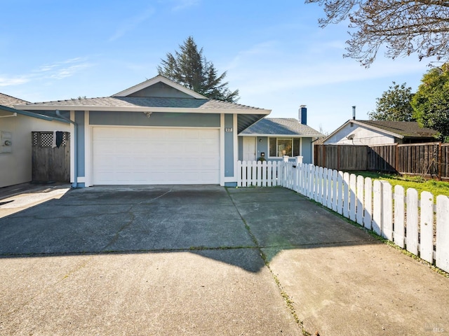 ranch-style home with driveway, a fenced front yard, and an attached garage