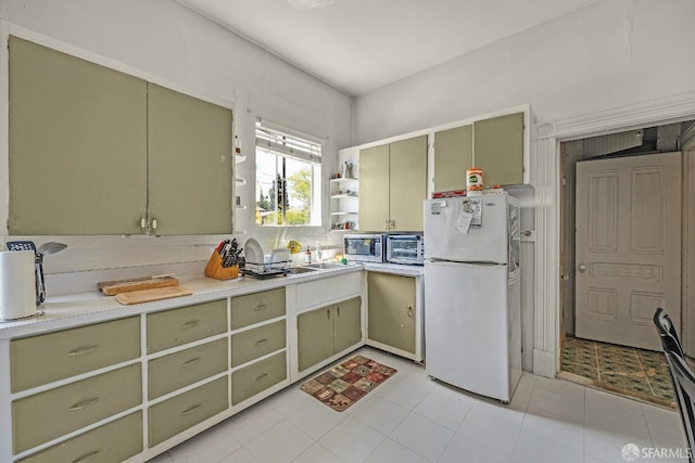 kitchen with white fridge, green cabinets, and sink