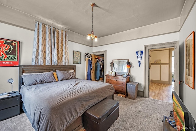 carpeted bedroom featuring a spacious closet, a closet, and a notable chandelier