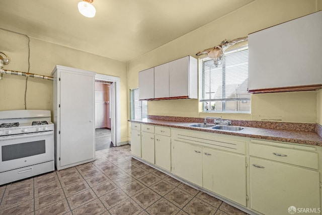 kitchen featuring white cabinetry, white gas range, and sink